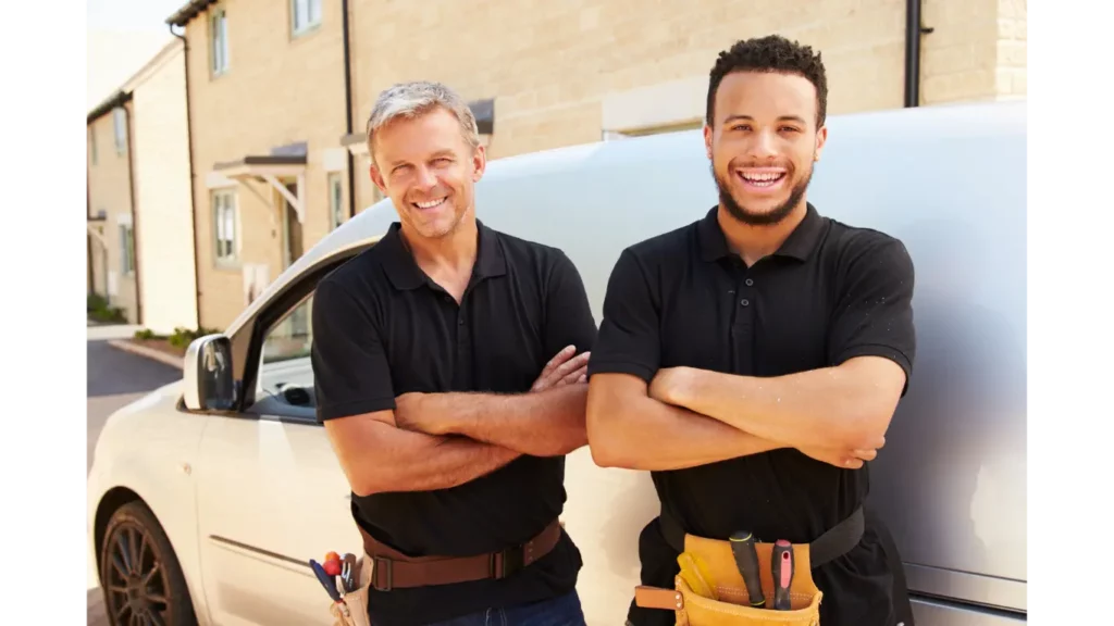 two contractors standing in front of a white van wearing toolbelts