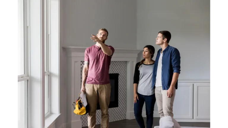 couple standing in a living room with a contractor pointing at details in the remodel