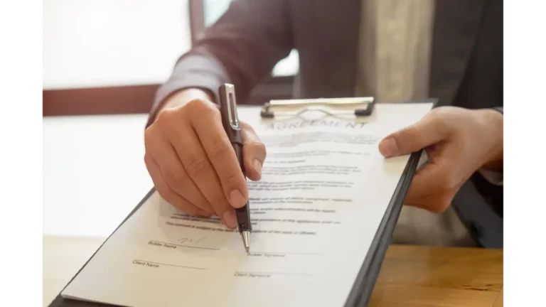 An agreement between a builder and client on a clipboard with a pen pointing at signature line