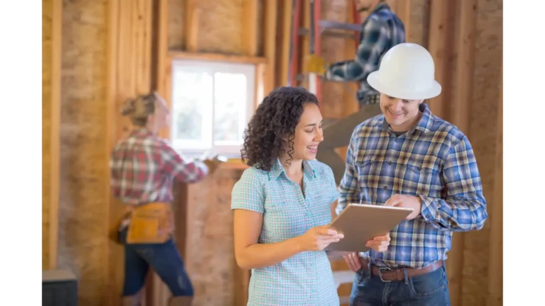 Lady standing with contractor reviewing details on a tablet with construction in the background