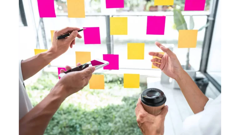 post it notes on a glass wall with hands pointing